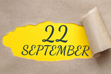 september 22. 22th day of the month, calendar date.Hole in paper with edges torn off. Yellow background is visible through ragged hole.Autumn month, day of the year concept