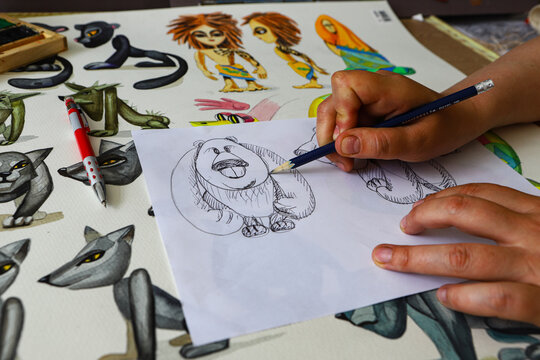 The animator draws with a pencil and draws characters from cartoons, comics or puppet shows. Mowgli's play. Preparing to make a doll. The designer creates sketches. Comics, cartoons, puppet theater
