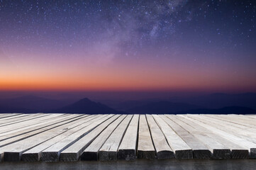 Naklejka na ściany i meble Empty old wooden table in front of blurred beautiful view on top the mountain and night sky, star, milky way, mountain, sunlight background. Can be used for display or montage for show your products.