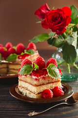 Cake. A piece of beautiful raspberry cake on a plate. Festive food. Bouquet of red roses in a vase. Postcard. Poster. High quality photo