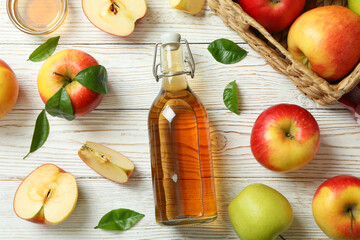 Homemade apple vinegar and ingredients on white wooden table