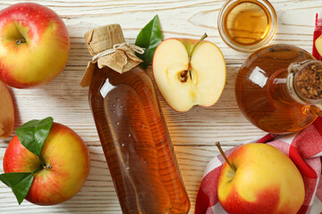Homemade apple vinegar and ingredients on white wooden table