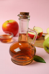 Homemade apple vinegar and ingredients on pink background