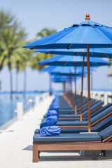 Blue Sun Umbrellas and Deck Chairs by a Swimming Pool