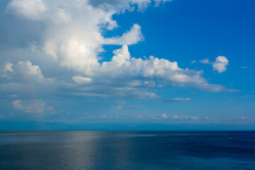 Cumulus clouds against the blue sky over Lake Baikal. Horizontal image.