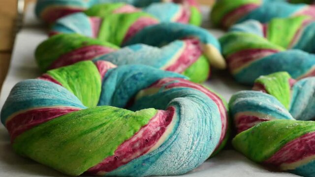 Home baked rainbow colored bagels on baking tray. Fun vibrant colors on the breakfast dough ready to be baked.