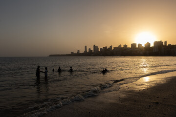Silhouettes of people and skyscrapers during sunset at Marine drive Beach in Mumbai Maharashtra India 