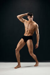 Obraz premium man with a pumped-up muscular body in black shorts posing against a dark background