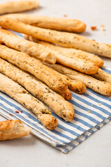 Homemade breadsticks with herbs on a gray concrete background. Grissini - Italian breadsticks