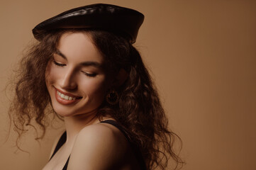 Happy smiling beautiful curly brunette woman wearing trendy faux leather beret. Close up studio portrait. Copy, empty space for text