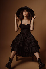 Fashion portrait of elegant confident  woman wearing wide bream hat, stylish black dress with...