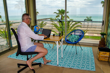 Man tele working from home dressed with a elegant shirt for videoconference and shorts and bared...