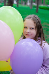 Fototapeta na wymiar pretty teenage girl with colorful balloons in purple costume in park. happy kids. summer days. vacation, holidays