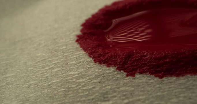 Red blood concept. Drops of blood drip onto a paper napkin, blood spreads over the napkin, macro shot.