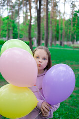 Fototapeta na wymiar pretty teenage girl with colorful balloons in purple costume in park. happy kids. summer days. vacation, holidays