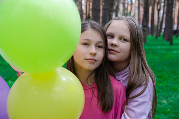 Fototapeta na wymiar two pretty teenage girls friends with colorful balloons in park. happy kids. summer days. vacation, holidays. friendship, girlfriends. bff