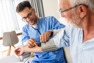 Male nurse measures blood pressure to senior man while being in a home visit.