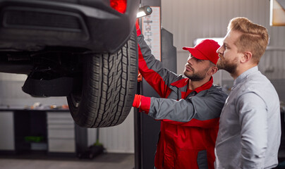 Mechanic with client examining car in garage