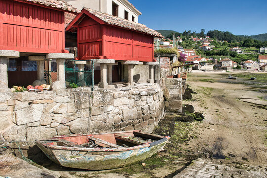 Vieja barca a remos abandonada junto a tradicionales h&oacute;rreos rojos durante la marea baja en la villa de Combarro, Galicia, Espa&ntilde;a