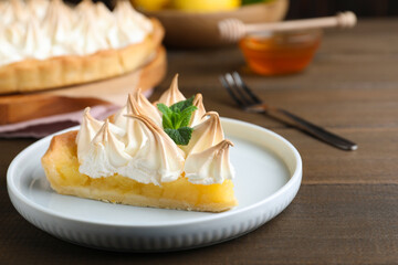 Piece of delicious lemon meringue pie with mint served on wooden table, closeup - obrazy, fototapety, plakaty