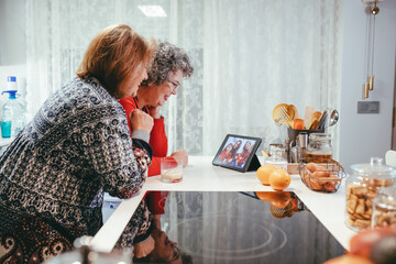 Grandmother lesbian couple having video call on tablet in kitchen