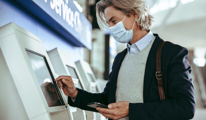 Business traveler with mask using self service check in at airport