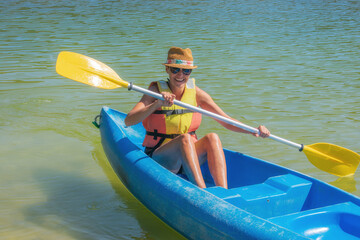 smiling woman in life jacket paddling a canoe on the river