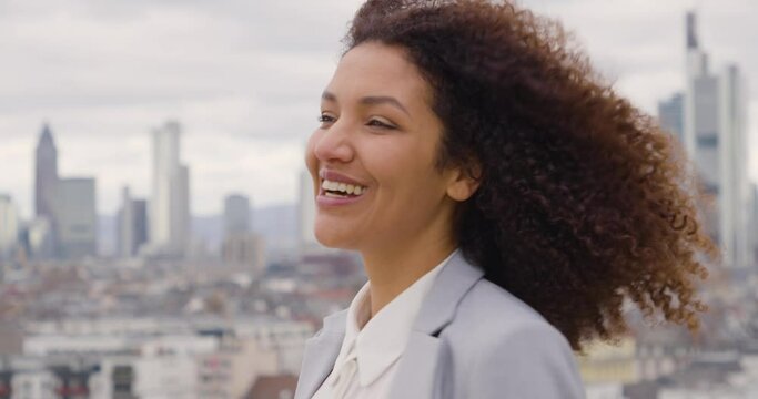 Laughing businesswoman standing on windy roof top terrace