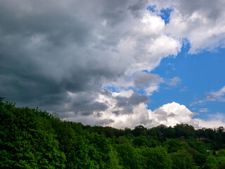 Obraz premium Massive dark storm clouds coming from right over a wooded hill