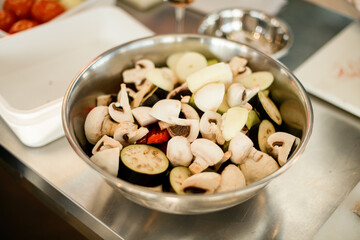 selective focus of sliced champignon and eggplant in steel bowl.