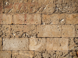 Aged and rustic stone wall abstract texture brown orange background. Big stone brick wall texture. Weathered abrasion stone of old building. Ancient brick wall background.