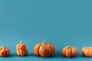 Handmade Pumpkins of different sizes stand in row against blue background