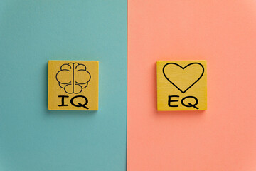 IQ and EQ on wooden cube over pink and blue pastel background use for emotional and intelligence quotient ,Opposites concept., - obrazy, fototapety, plakaty