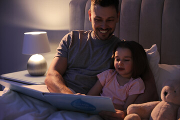 Father reading bedtime story to his daughter at home - obrazy, fototapety, plakaty