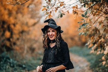 Girl dressed as witch laughs on the background of the forest