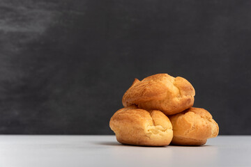 Profiteroles or popovers, eclairs side view. Three appetizing profiteroles. Gray background. Copy space