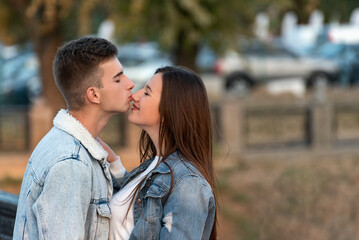 Fototapeta premium Guy gently kisses his girlfriend in the nose. Portrait of loving couple. Romantic date in the city.