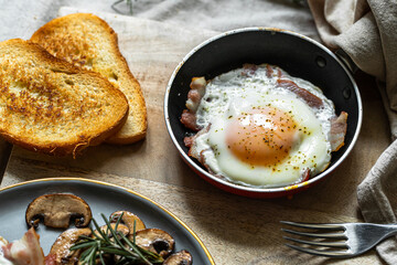 Breakfast with fried egg(sunny side up) with bacon, grilled with rosemary mushrooms and toast with cream cheese