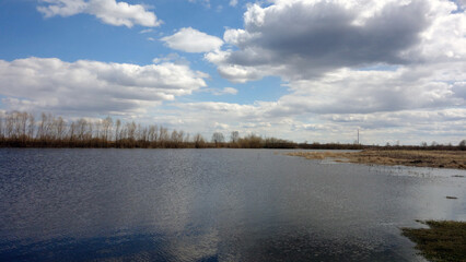 Spring siberian landscape - lake and clouds. Clear and calm water. 