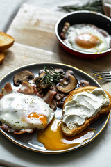 Breakfast with fried egg(sunny side up) with bacon, grilled with rosemary mushrooms and toast with cream cheese