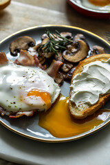 Breakfast with fried egg(sunny side up) with bacon, grilled with rosemary mushrooms and toast with cream cheese