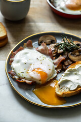Breakfast with fried egg(sunny side up) with bacon, grilled with rosemary mushrooms and toast with cream cheese