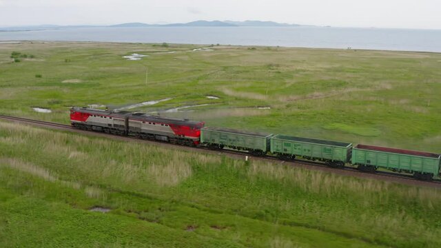 A drone view of a freight train driven by a diesel locomotive on a railroad