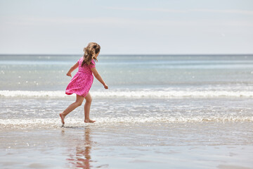 Fototapeta na wymiar typical image of summer with a young girl running on the beach