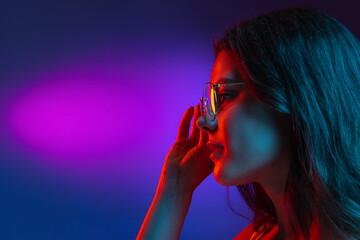 Caucasian young woman's portrait on dark studio background in neon. Concept of human emotions,...