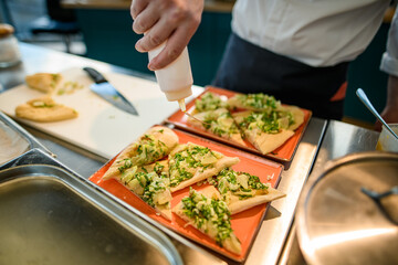 plates with slices of pizza stuffed with greens and cheese and male chef pours sauce on its