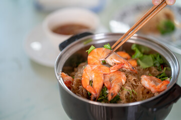 Chopstick holding cooked shrimp at hotpot. 