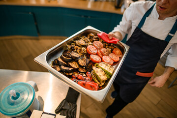 baking sheet with various healthy baked vegetables in hand of chef