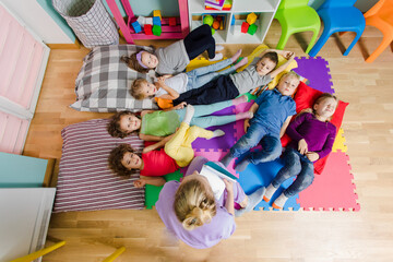 Active kids laying on soft pillows and mats at the kindergarten