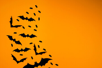 Flying flock of bats on orange background mockup. Halloween holiday concept. Black silhouettes . Empty space for text. Copy space.